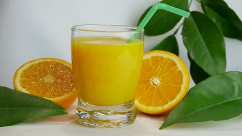 Studio shot of full glass of orange juice and orange halves, closeup, slow pan