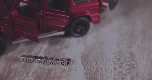 Toy Car Next to Block Letters Spelling Insurance