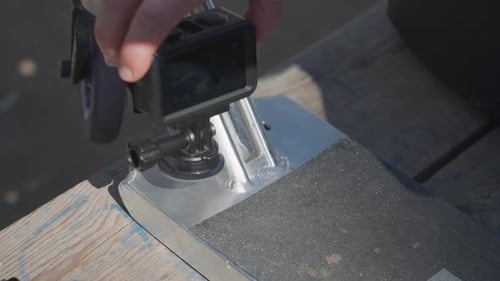 Man hold small action camera and stick it to stunt scooter aluminum deck