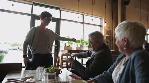 Daughter Hugs Happy Senior Parents in Cafe
