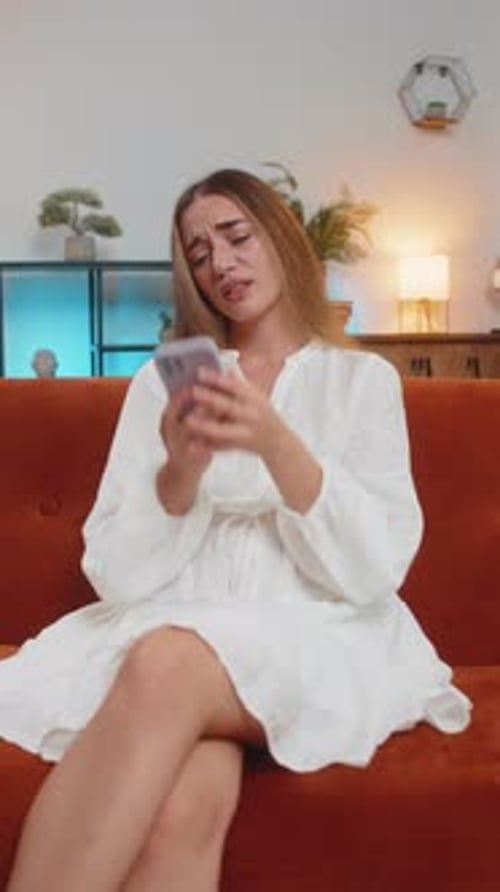 Woman Crying While Using her Smartphone Indoors
