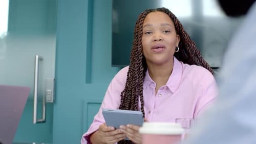 Segurando o tablet, mulher discutindo o trabalho com colegas em reunião de escritório