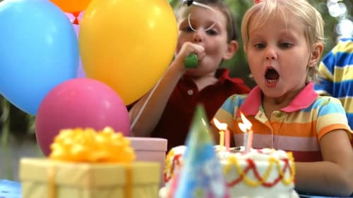 Girl blows out candles at colorful birthday party