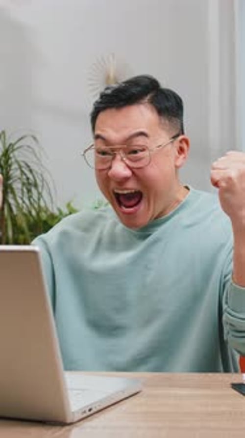 Man Celebrates Success in Front of His Laptop