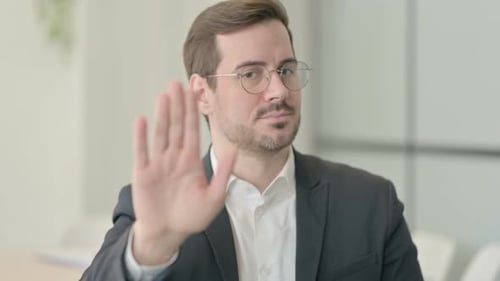 Businessman Holds Hand Up in Stop Gesture Indoors