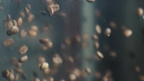 Grains de café torréfiés tombant sur un fond sombre