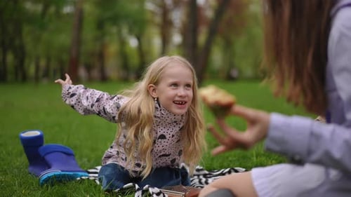Happy Little Girl Eating a Treat at Picnic