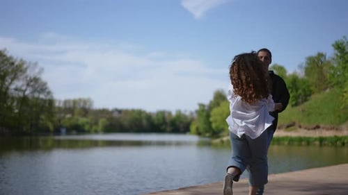 A Lovely Couple Holding Hands By the Water in a Beautiful Scenic Park During Daylight
