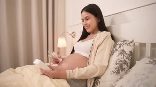 Femme enceinte tenant un doppler foetal de poche pour écouter le rythme cardiaque du bébé sur le ventre