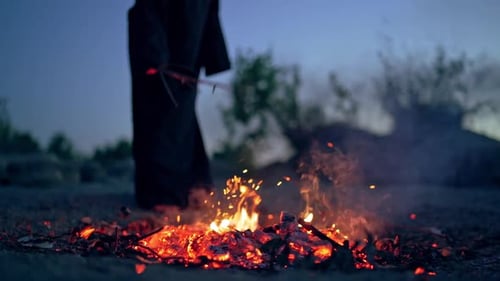 Mysterious Figure Standing Near Fire at Night