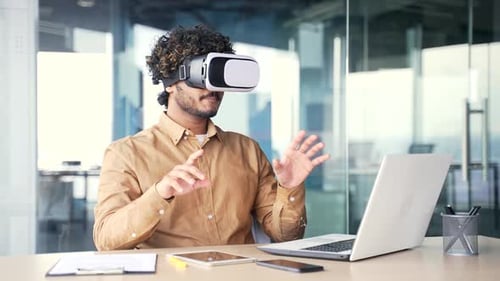 Young successful manager works using VR glasses in virtual reality simulator while sitting
