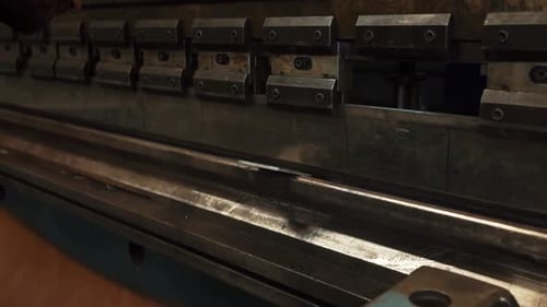 Man working with sheet metal on CNC hydraulic press brake. He puts the part and bends it into a
