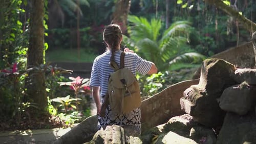 Female tourist with backpack is enjoying view of a forest