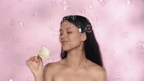 Closeup Studio Shot of Beautiful Female Model Brunette Girl Holding Rose Flower and Looking at the