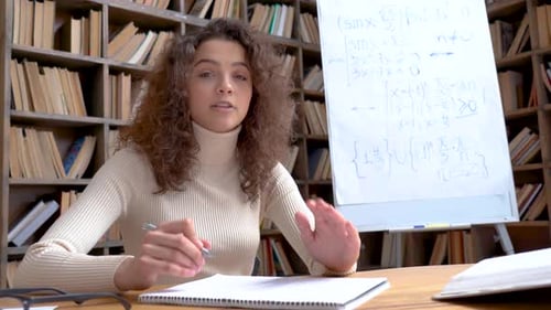 Woman Explaining Math in a Library Setting