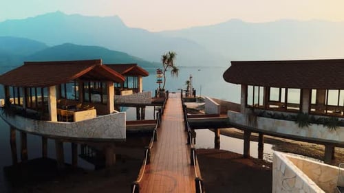 Bangalôs sobre a água e um píer de madeira se estendem até as águas calmas do lago, emolduradas por