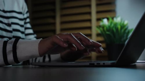 Close up of a woman hands typing on laptop keyboard in the night at home