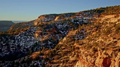 Superbes images prises par Drone d'un canyon multicolore au lever du soleil, avec un terrain accidenté et une végétation clairsemée