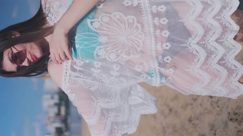 Beautiful, attractive, happy girl posing on a sandy beach on a sunny day wearing a blue swimsuit, su
