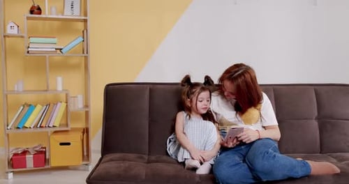 Woman and Child Watching Phone on Couch