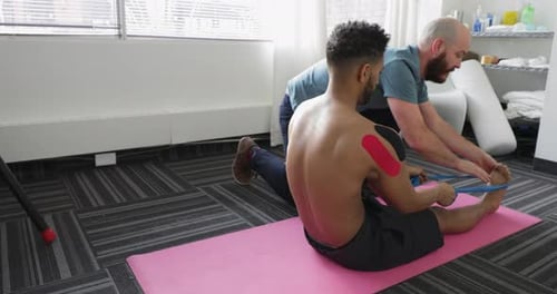 Man Stretches Legs with Assistance from Physical Therapist