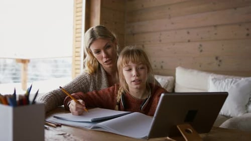 Mother with Small Daughter Doing Homework Indoors at Home, Home School Concept
