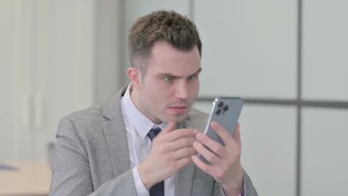 Man Reacts to News on Phone in Office