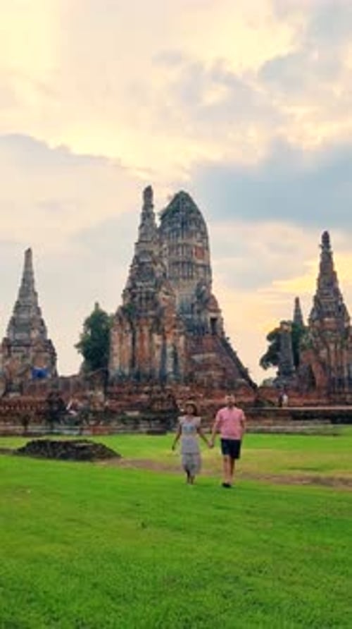 Deux personnes se promenant sur un champ herbeux près d'un temple médiéval sous un ciel nuageux Ayutthaya, Thaïlande