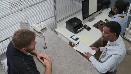 Bank Clerk Explaining Terms of Service Agreement to Client in Office