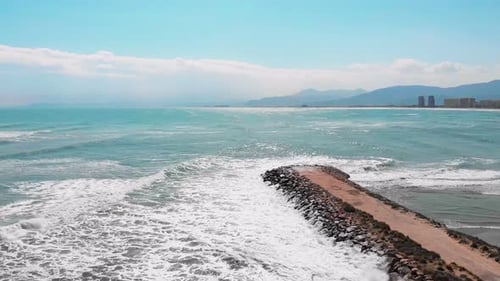 Seashore of Mediterranean Sea with turquoise sea water with mountains and skyscrapers on background
