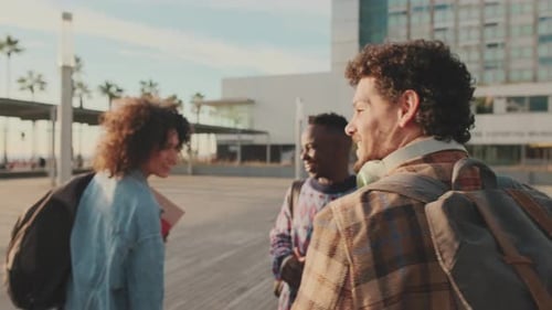 Happy diverse students chatting and laughing walk together down the street