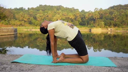 Jeune fille indienne faisant du yoga ustrasan en Inde Mumbai, pose de backbend yogsana au bord du lac