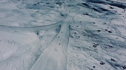La gente va cuesta abajo en una pista de esquí blanca, aérea