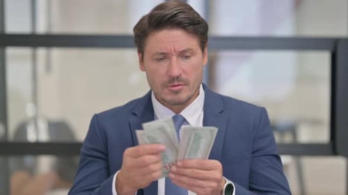 Man in Suit Counting Money in Office