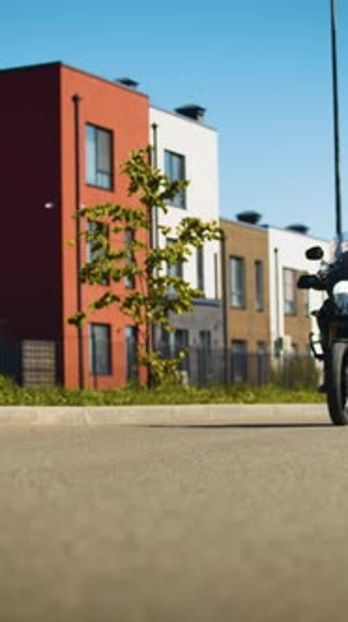 A Biker Rides His Motorcycle By the City Street Passing the Camera
