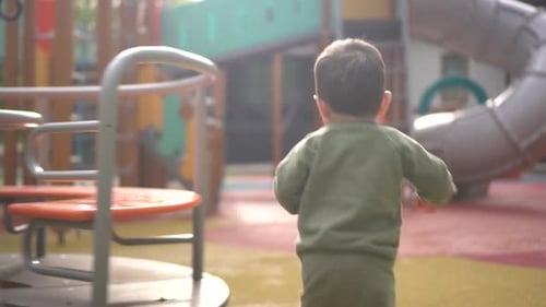 A Twoyearold Child Walks on a Playground Among Slides and Swings Little Son in the Park
