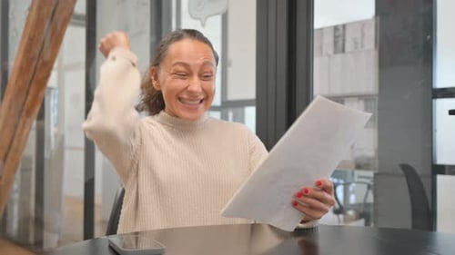 Excited Woman Reads Documents at Table
