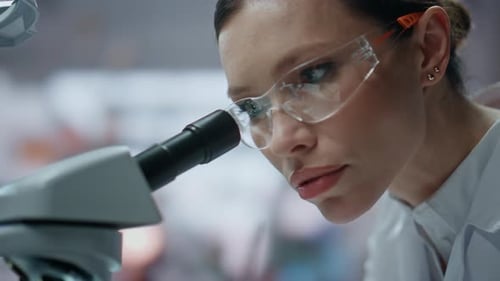 Biochemiker aus nächster Nähe schaut mit dem Mikroskop auf die Probe im Kliniklabor