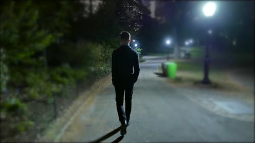 Young Man Walking on Street Alone in Dark Night