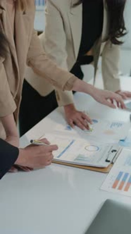 Collaborative Businesswomen and Man Discussing Charts in Office