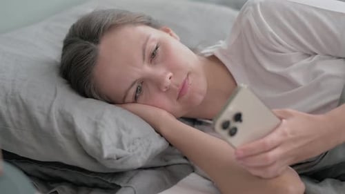 Woman Lies in Bed Using Smartphone