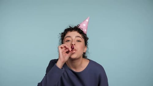 Close Up Happy Curly Woman in Birthday Cap Blowing Whistle Celebrating Holiday