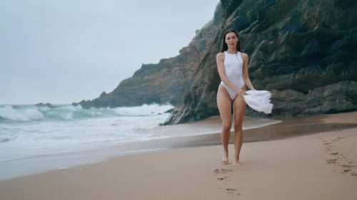 Woman in Swimsuit Walking on Beach During Overcast Day