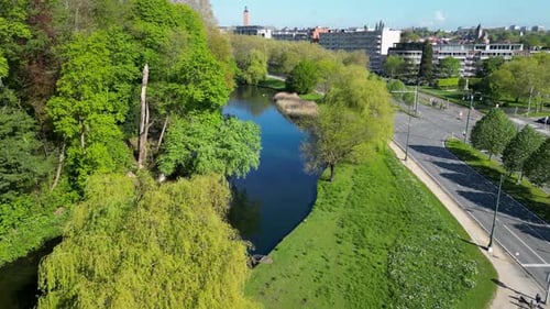 Aerial view of a lush park with a pond and tram tracks, Belgium.