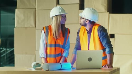 Ingenieure arbeiten mit Laptop und Bauplänen an einem Bauprojekt zusammen