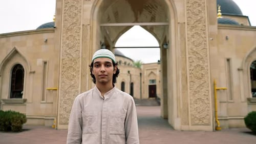 portrait of a young Arab man looking into the camera against the background of Muslim mosque