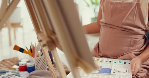 girl painting canvas with color palette use paint brush focus on painting abstract on weekend.