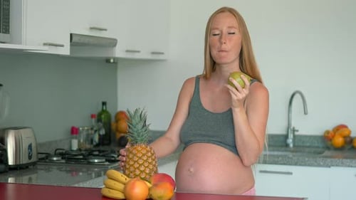 Pregnant Woman Eating Healthy Fruit in Kitchen