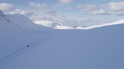 Mountain valley with a road covered in snow, winter panorama. Aerial view.