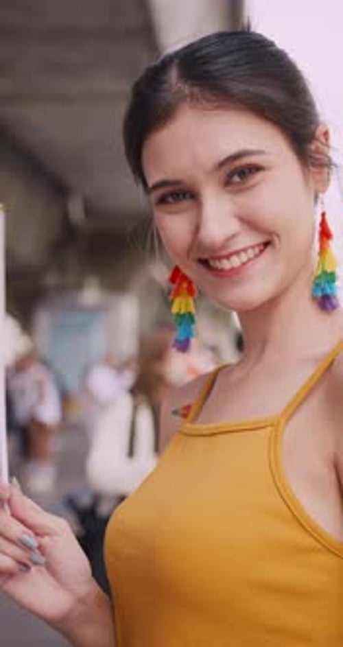 Vertical clip. A young woman shows off her homosexual identity in a pride parade.